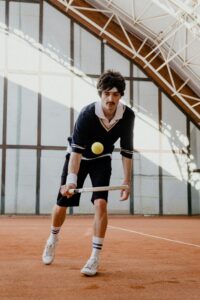 A male tennis player with a vintage style outfit in a dynamic indoor match.